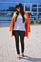 Skórzane spodnie, bluzka z baskinką i pomarańczowy płaszcz