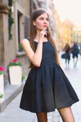 Elegancka czarna rozkloszowana sukienka, czarne rajstopy i szpilki