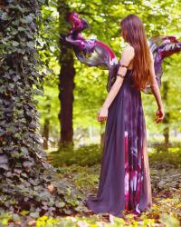Długa fioletowa suknia w kwiaty i złote bransoletki na ramię