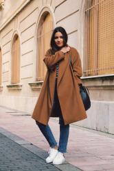 abrigo marrón, top de rayas y zapatillas