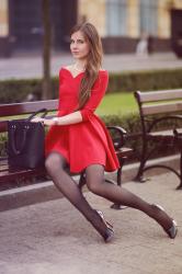 Czerwona rozkloszowana sukienka, czarne rajstopy i eleganckie szpilki
