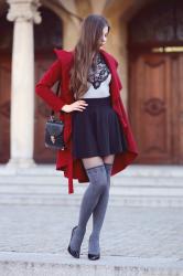 Czerwony długi płaszcz, szara bluzka, czarna spódniczka i szare zakolanówki