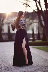 Czarna długa suknia z rozcięciem, cieliste rajstopy i szpilki