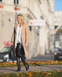 Winter Outfit Klassiker: Camel Wollmantel, schwarze Lederstiefel & weiße Bluse.