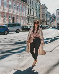 Outfit mit Trenchcoat, gemusterter Bluse, schwarzer Skinny Jeans und Pumps