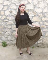 Look vintage en jupe longue plissée, top noir et sandales compensées
