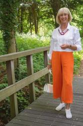White cropped blouse jacket with orange trousers